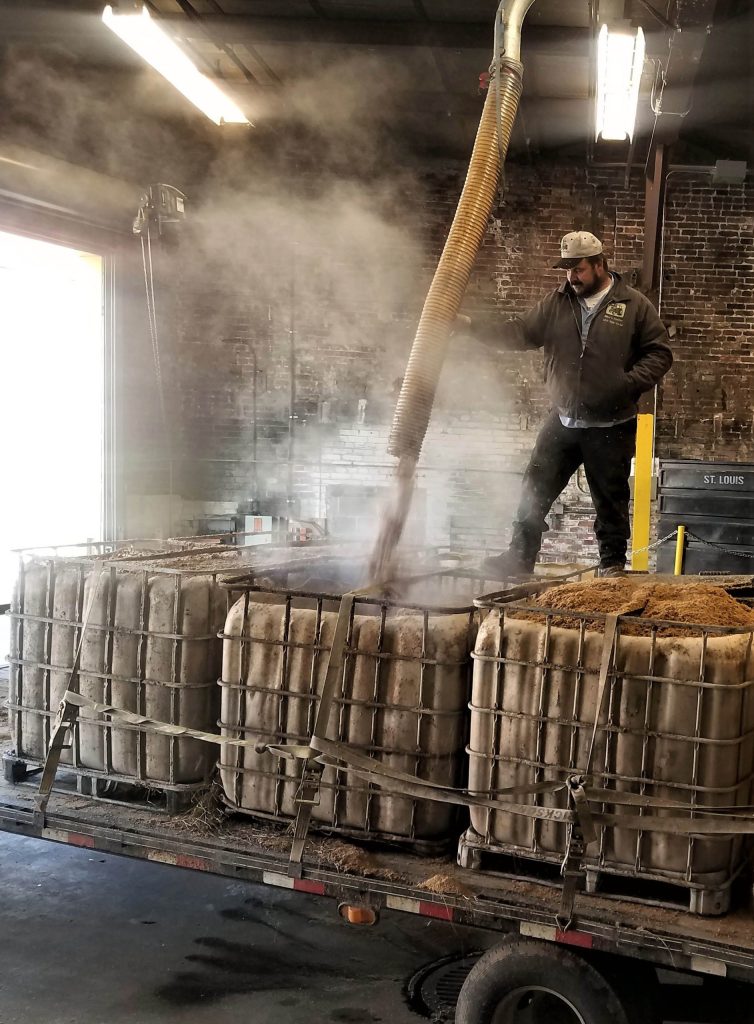 Brewer filling grain bins for farmer